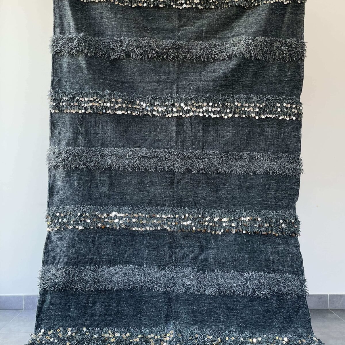 Apportez une touche de douceur et de lumière avec cette couverture berbère grise à sequins. Confortable et faite à la main